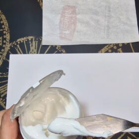 nell'immagine c'è un foglio bianco, con una spatola che sta prendendo da un contenitore una pasta morbida e di colore bianco