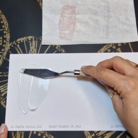 in questa immagine una spatola sta spalmando su un foglio bianco una crema bianca